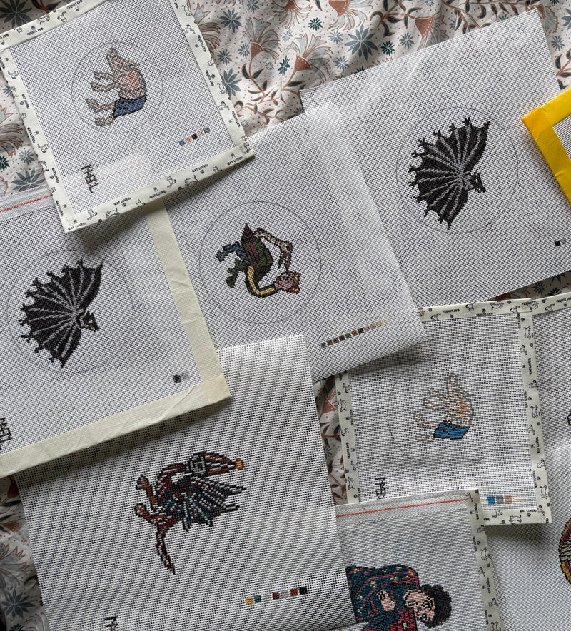 Several embroidered fabric panels with various animal and fantasy character designs are arranged on a patterned fabric background. One panel is highlighted with a bright yellow border.